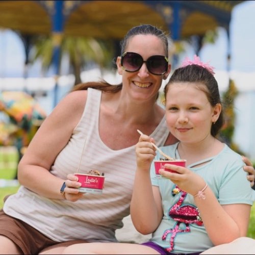 Mother and daughter enjoying desserts on the grass